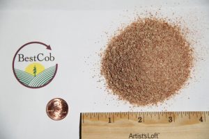 Close-up of a pile of brown sand or soil with a BestCob logo and a ruler for scale.