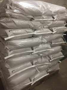 Stacked white bags of Best Cob fertilizer on pallet for sale.