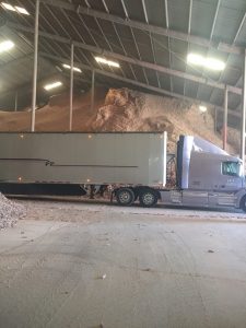 Large truck inside warehouse storing cob materials for construction.