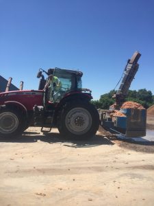Heavy-duty tractor with conveyor belt for cob processing at construction site.
