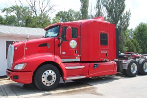 Red semi-truck with Best Cob logo parked outdoors on a sunny day.