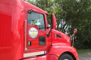 Red Best Cob truck parked outdoors with trees in the background.