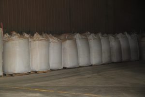 Large white bulk bags stored in a warehouse for construction materials.