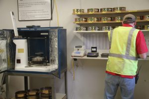 Worker in safety vest inspecting jars of best cob products in a storage room.