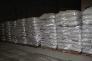 Stacks of white packaged materials stored on pallets in a warehouse.