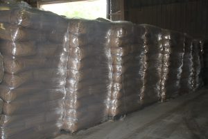 Stacked bales of hay or straw wrapped in plastic in a warehouse.