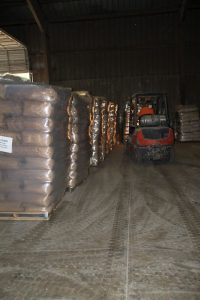 Warehouse with stacked bags and a forklift at Best Cob facility.