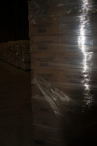 Stacked boxes wrapped in plastic on a warehouse floor for Best Cob products.