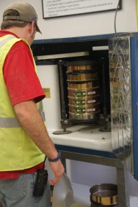 Technician operating a large industrial machine with a metallic drum at Best Cob.
