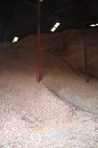 Large pile of red and pink gravel inside a warehouse with support beams.