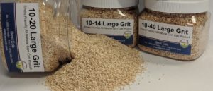 Containers of large grit corn cob product with spilled grit on surface.