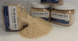 Assorted sizes of Best Cob corn grit products in jars with spilled grit on surface.