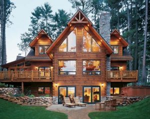 Luxury wooden cabin with large windows and outdoor deck in forest setting.