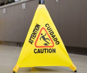 Yellow caution sign with 'Attention' and 'Cuidado' warnings on a tripod stand.