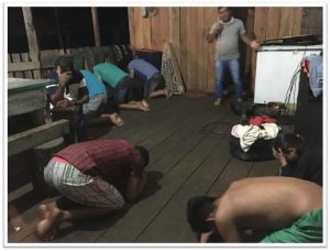People praying on the floor in a wooden room at Best Cob.