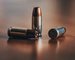 Three bullets on a wooden surface, close-up of ammunition for firearms.