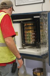 Worker inspecting a metal industrial machine with stacked components at Best Cob facility.