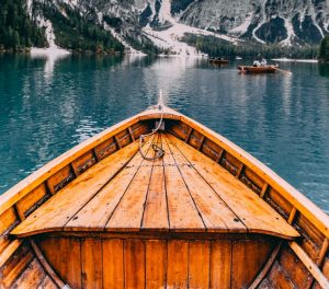 View from a wooden boat on a mountain lake with snow-capped peaks in the background.