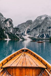 A wooden boat on a mountain lake with towering peaks in the background.