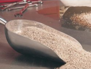 Close-up of a metal scoop filled with fine gravel or sand for construction.