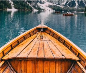 Wooden boat on calm lake with mountains in background.