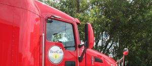 Red Best Cob truck parked outdoors with green trees in the background.