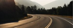 Scenic mountain road with curves and forested landscape in the background.