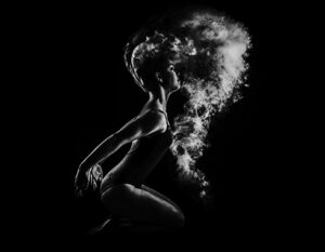 Silhouette of a woman exhaling vapor in a dramatic black and white photo.