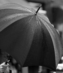 Close-up of a black umbrella with raindrops in black and white.